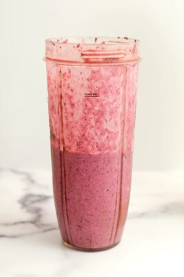 Pineapple blueberry smoothie ingredients in a blender cup after being blended.