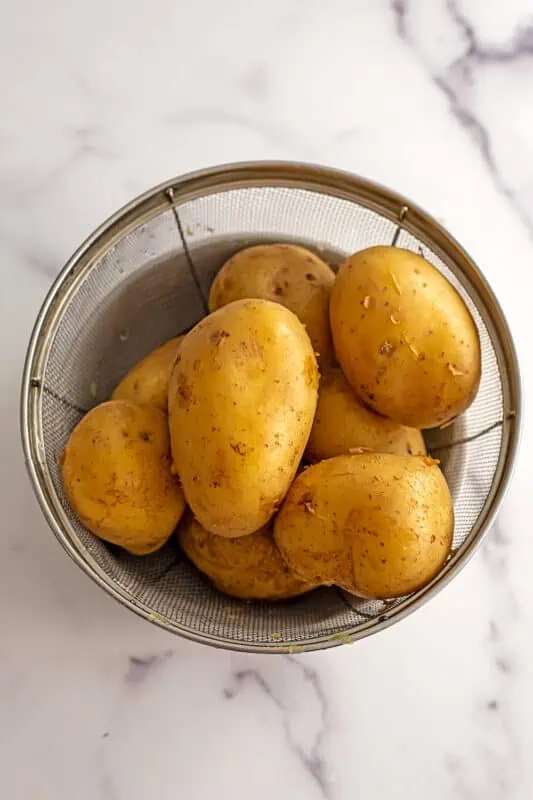 Gold potatoes in a mesh strainer.