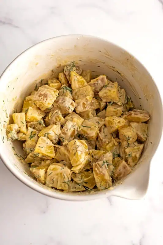 Dill potato salad after stirring in a large white bowl