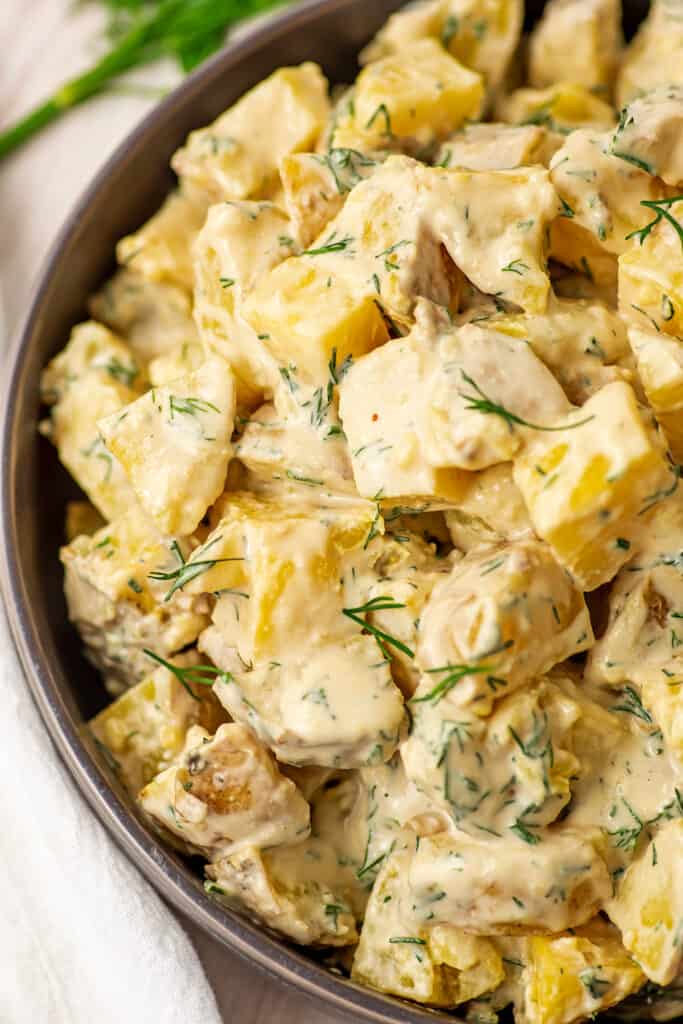 Tahini potato salad in a large gray bowl on a white table.