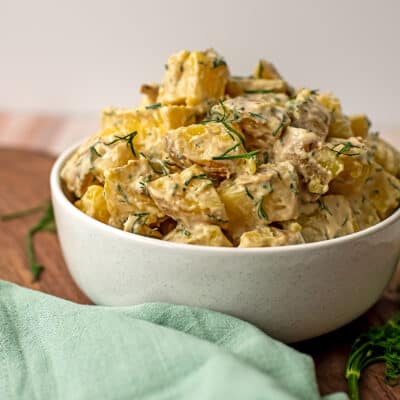 Tahini potato salad piled high in a white bowl.