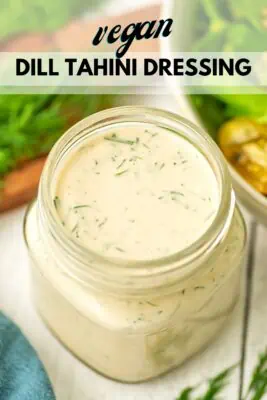 Vegan dill dressing in a bottle on a table next to a salad.