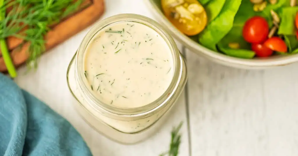 Vegan dill dressing on a wooden white table.