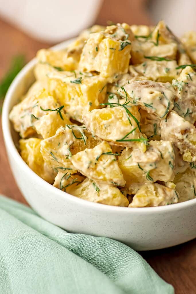Vegan dill potato salad in a white bowl on a table.