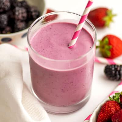 Blackberry smoothie without banana in a small glass with a straw.