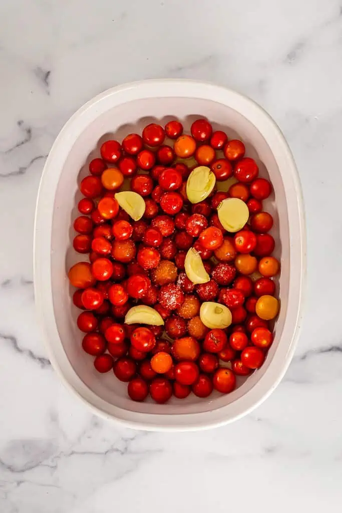 Cherry tomatoes and garlic in a casserole dish.