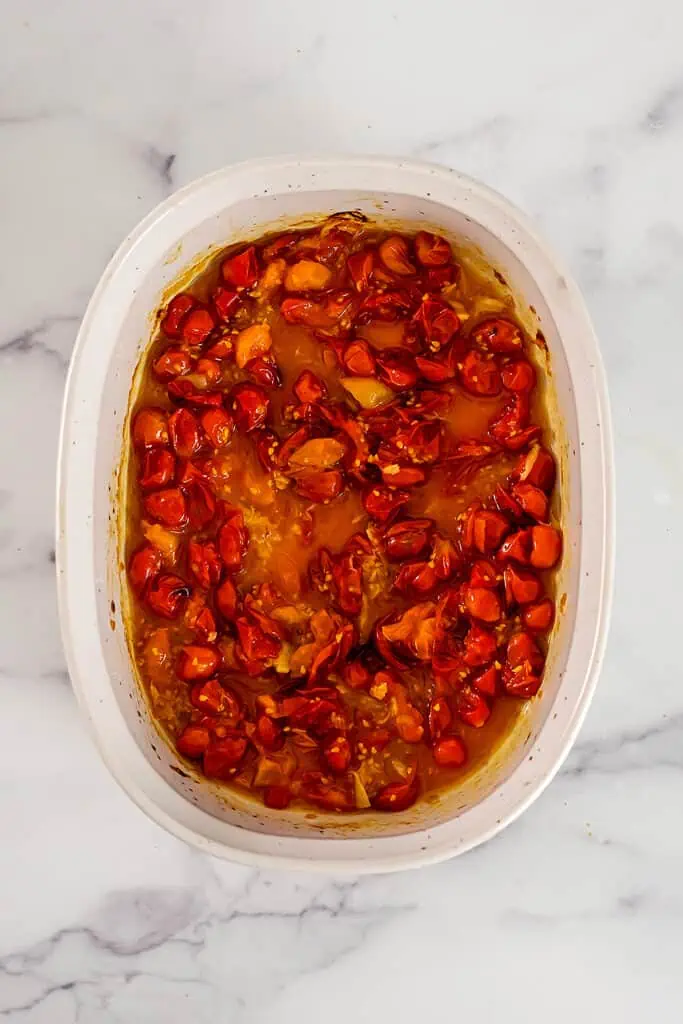 Roasted cherry tomatoes and garlic mixed up in a casserole dish.