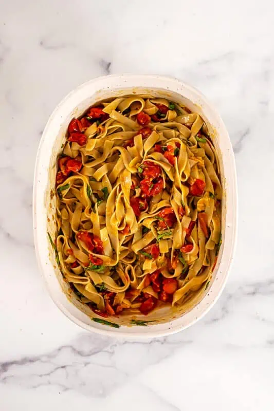 Cherry tomato pasta in a large white casserole dish on a marble countertop.