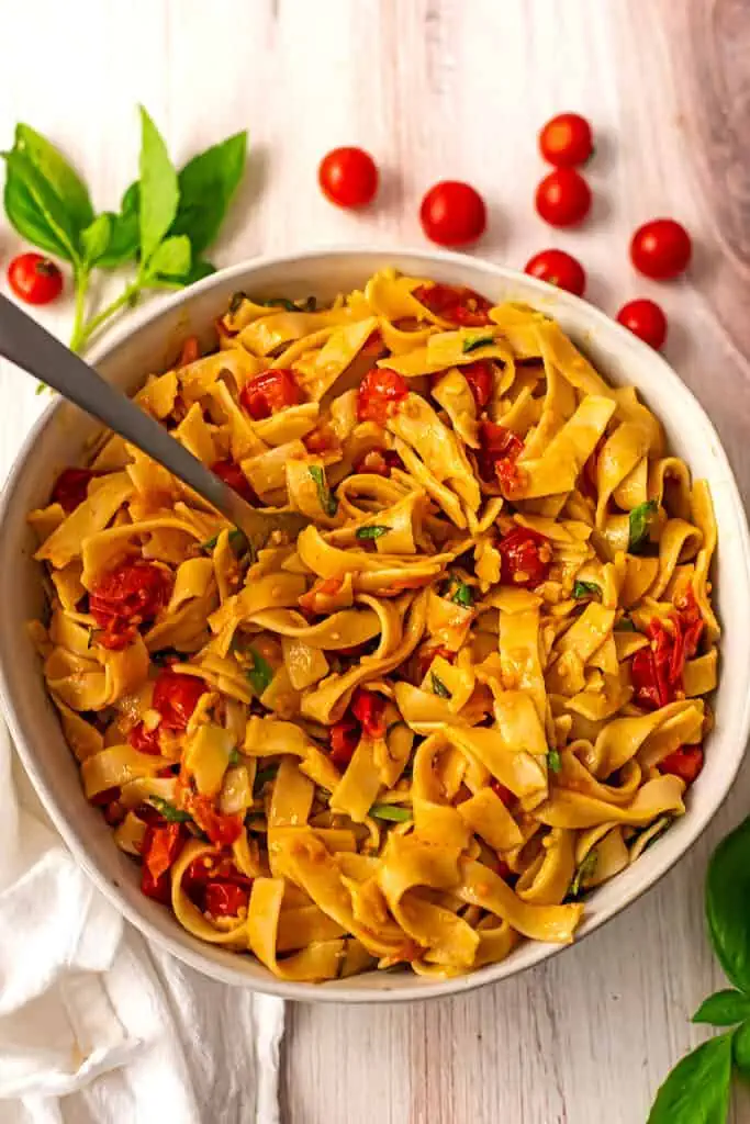 Cherry tomato pasta sauce mixed with pasta in a white dish.