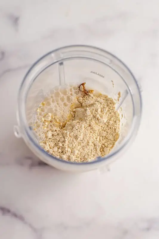 Cookie dough smoothie bowl ingredients in a blender cup before initial blend.