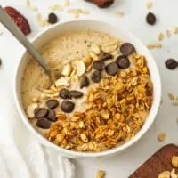 Cookie dough smoothie bowl on a white table with granola and chocolate chips on top.