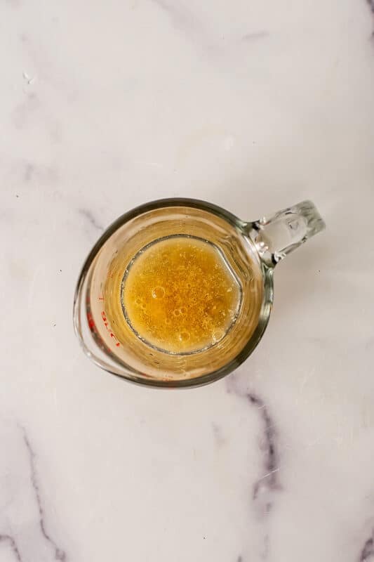 Glass measuring cup filled with tahini and apple cider vinegar. 