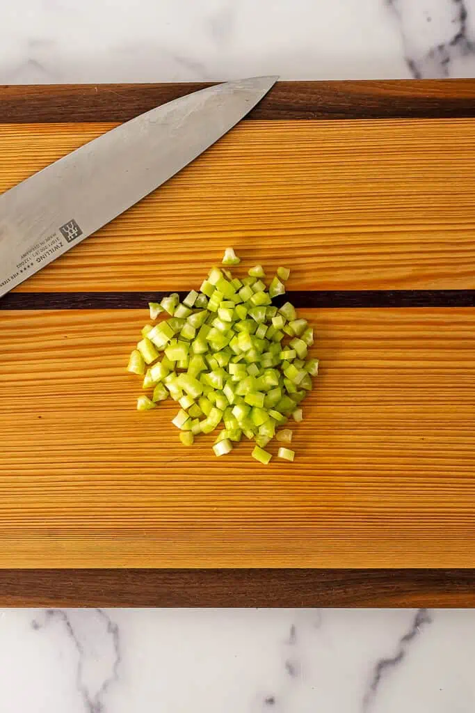 Finely chopped celery on wood cutting board. 