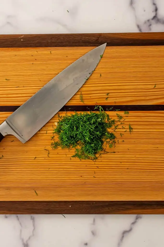 Finely chopped dill on a wood cutting board.