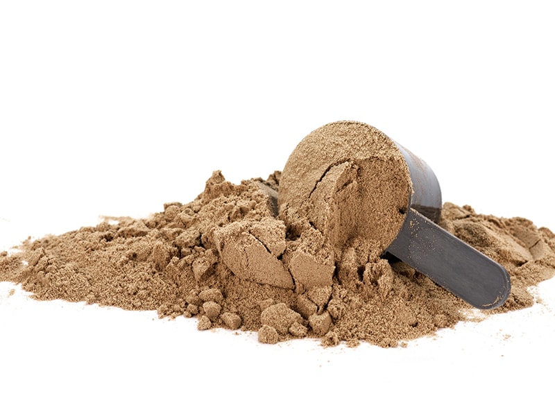 A scoop of chocolate protein powder spilled out on it's side.