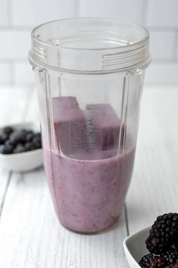 Meal prepped smoothie ice cubes being blended in a blender cup.