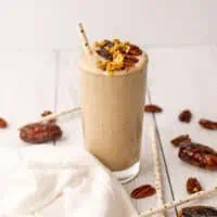 Pecan pie smoothie on a white table with a straw.