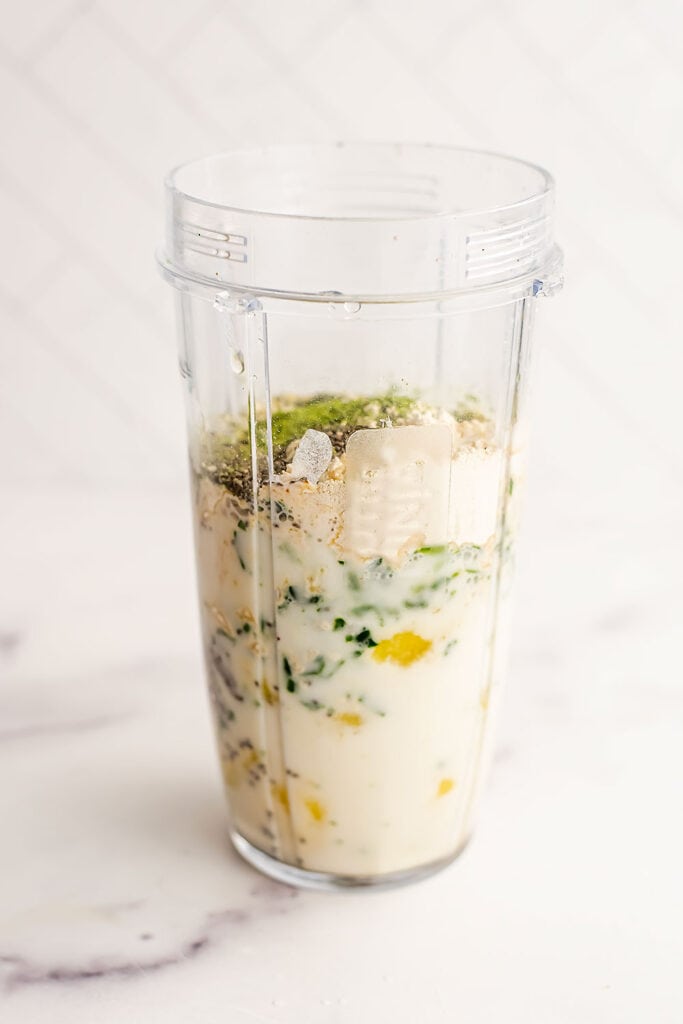 Pineapple matcha smoothie ingredients in a blender cup before blending.