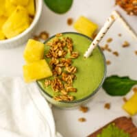 Matcha pineapple smoothie with bits of granola and chunks of pineapple on top.