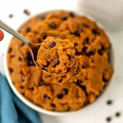 Protein cookie dough in a white bowl being spooned out.