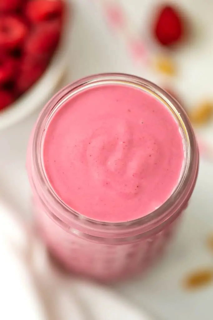 Raspberry and peanut butter smoothie in a tall glass.