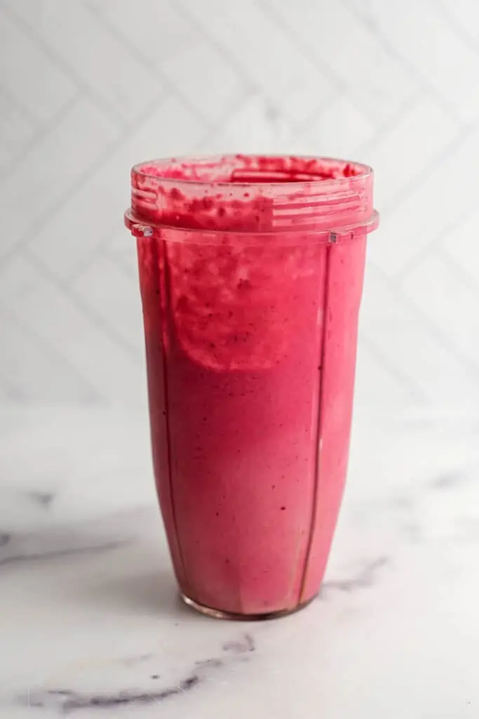 Raspberry peanut butter smoothie ingredients in a blender after being blended.