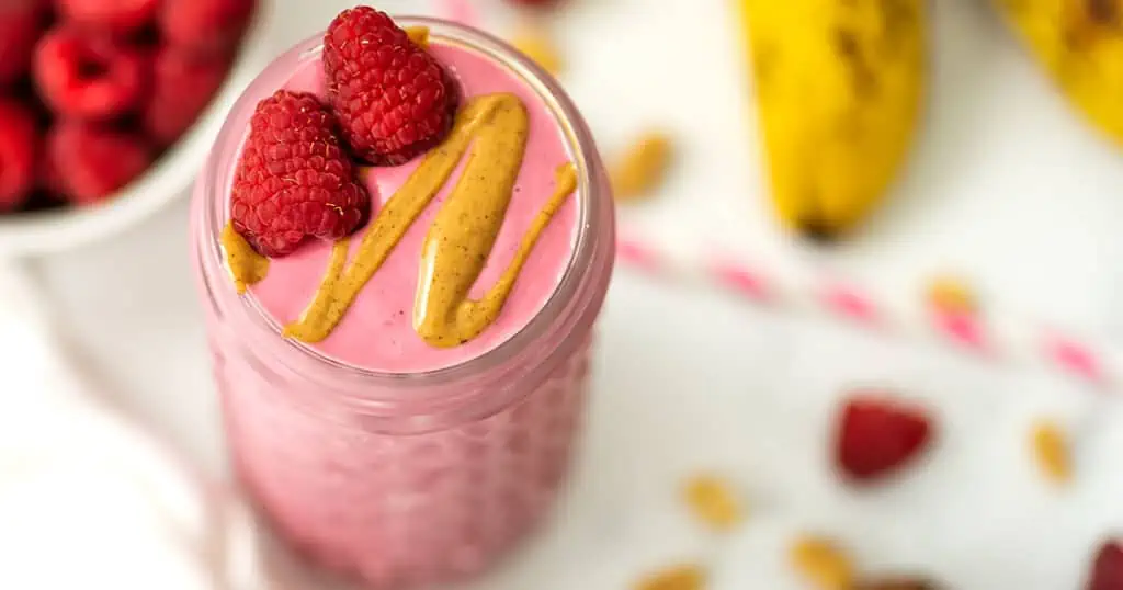Raspberry peanut butter smoothie with raspberries and peanut butter on top. 