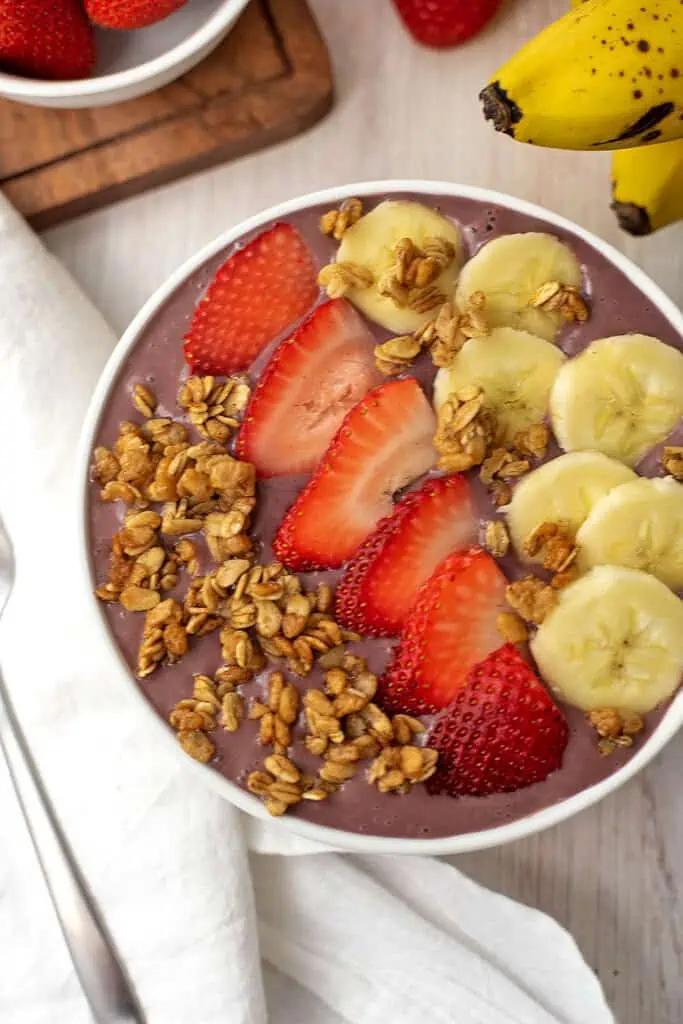 Strawberry and banana smoothie bowl with granola, banana and strawberries on top.