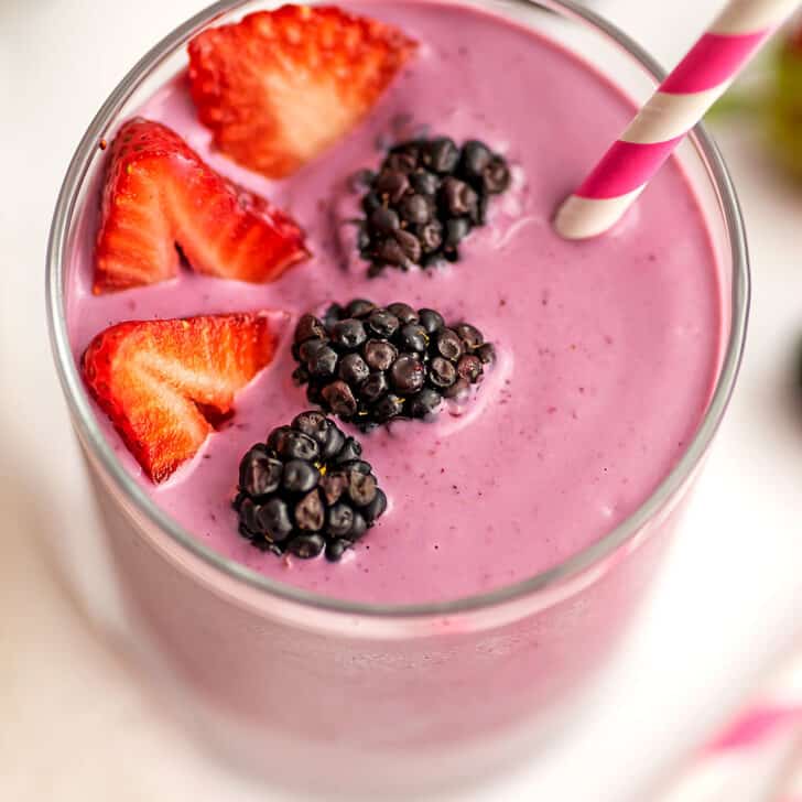 Overhead view of a strawberry and blackberry smoothie with blackberries and sliced strawberries on top.