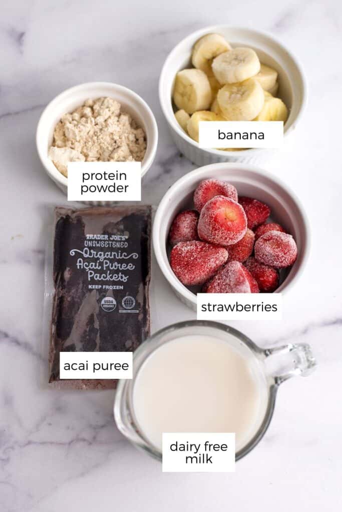 Strawberry banana acai bowl ingredients in white ramekins.