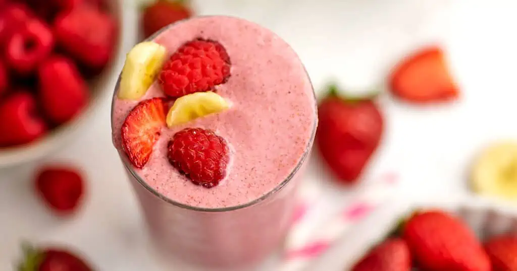 Strawberry banana raspberry smoothie with fruits as a topping.