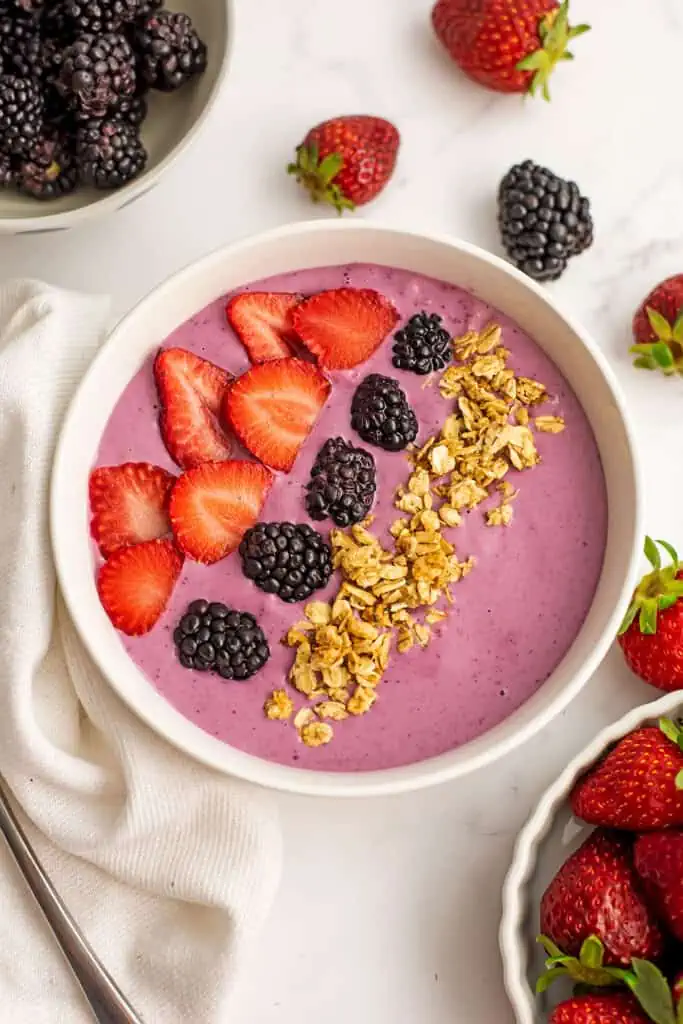 Strawberry blackberry smoothie recipe in a smoothie bowl with sliced strawberries, blackberries and granola on top.