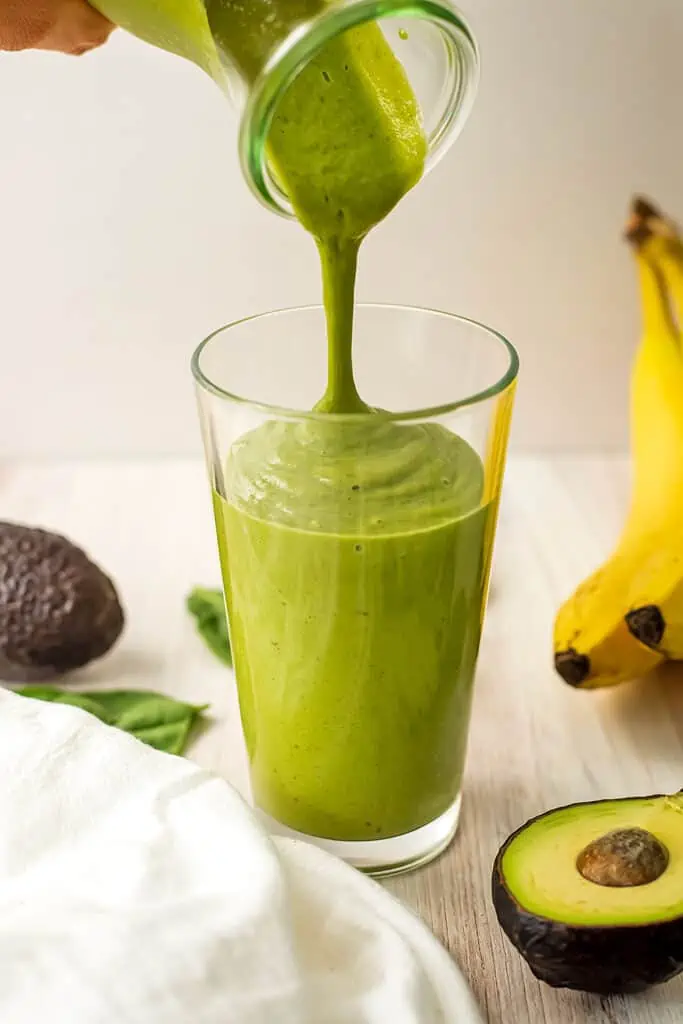 Avocado date smoothie being poured into a  glass.