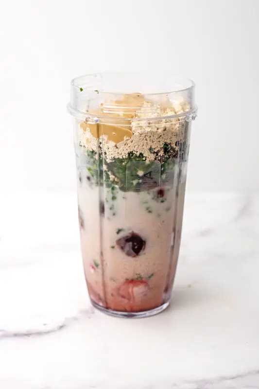 Cherry kale smoothie ingredients in a blender cup before blending.