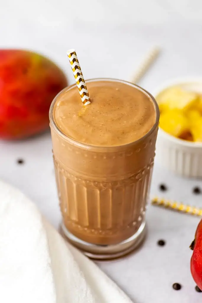 Chocolate mango protein smoothie with a straw.