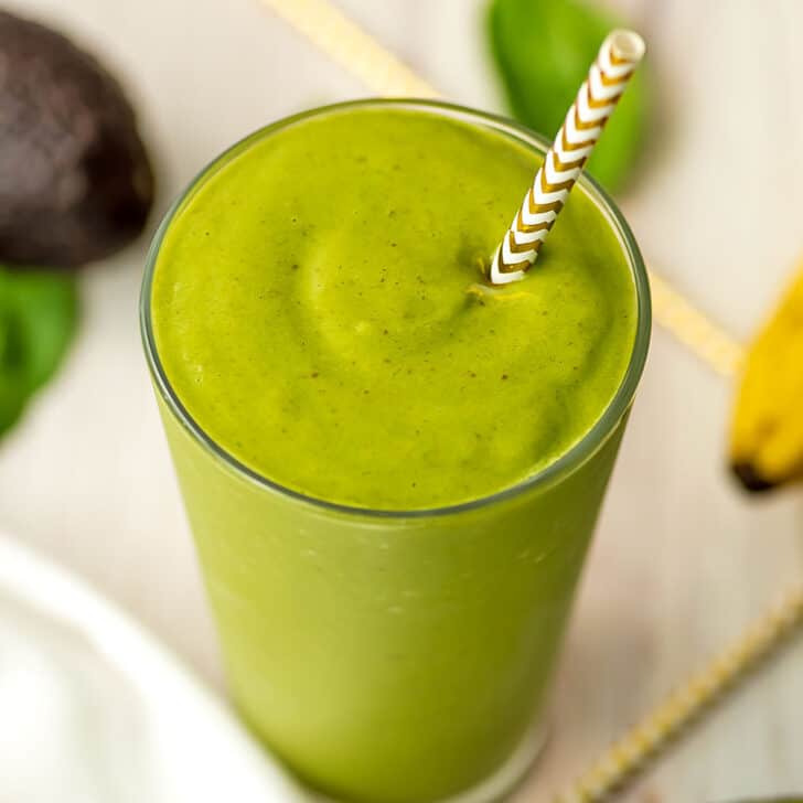 Date avocado Smoothie in a glass with a straw.