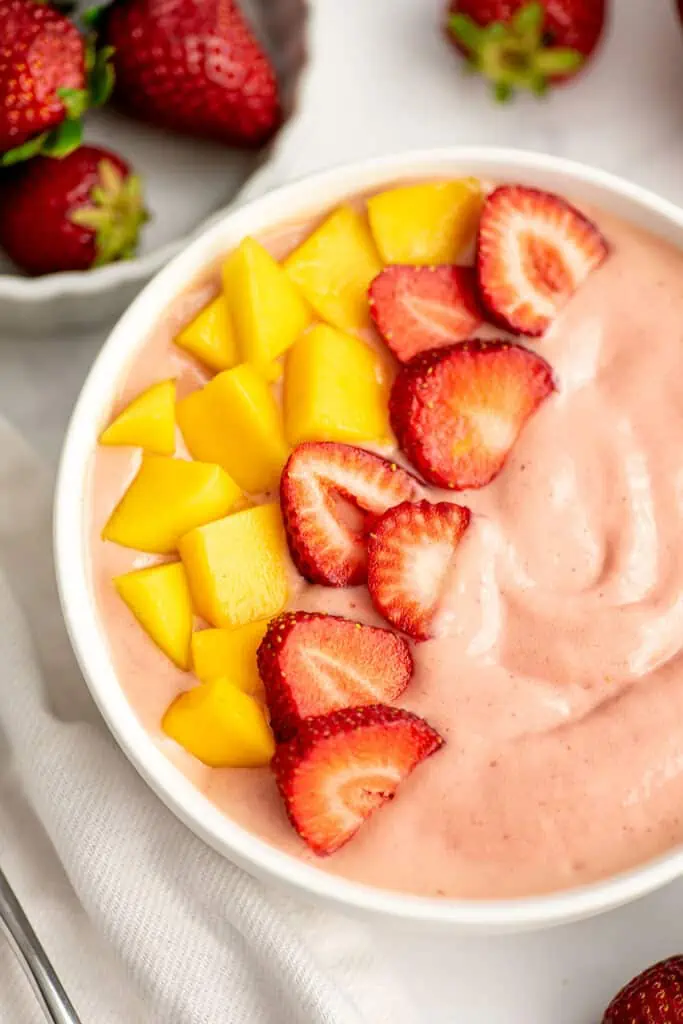 Mango strawberry smoothie bowl with freshly sliced mango and strawberries on top.