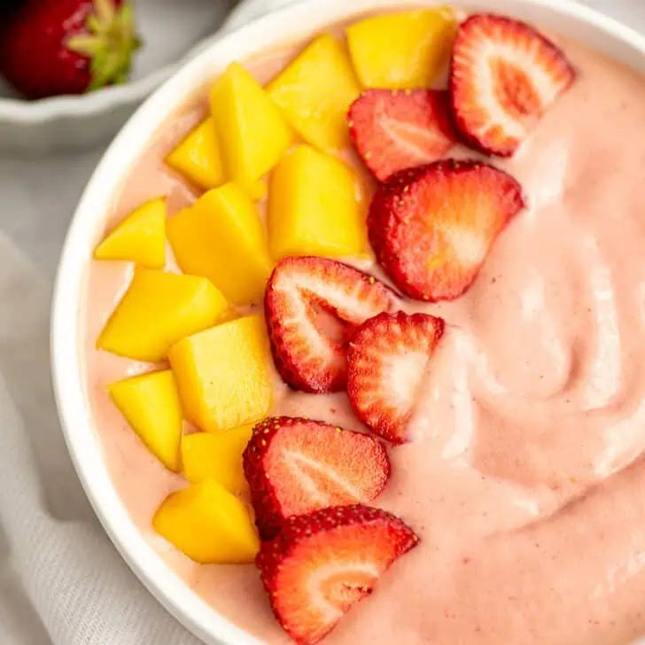Mango strawberry smoothie bowl with freshly sliced mango and strawberries on top.