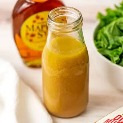Maple dijon vinaigrette in glass bottle with white napkin on the side.