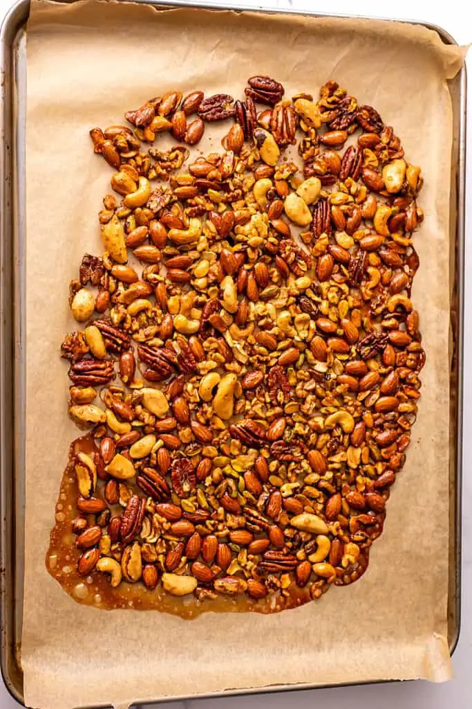 candied maple nuts on parchment paper lined baking sheet after roasting.