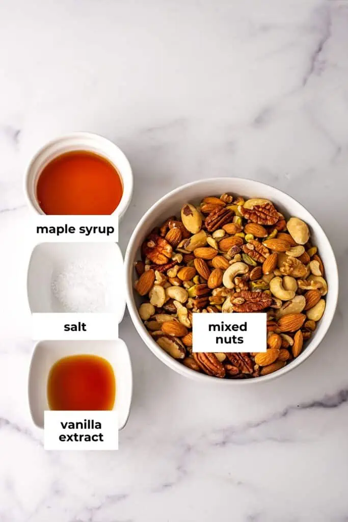 Ingredients to make maple nuts in bowls on marble countertop.