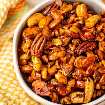 Bowl filled with candied maple nuts with yellow napkin on the side.