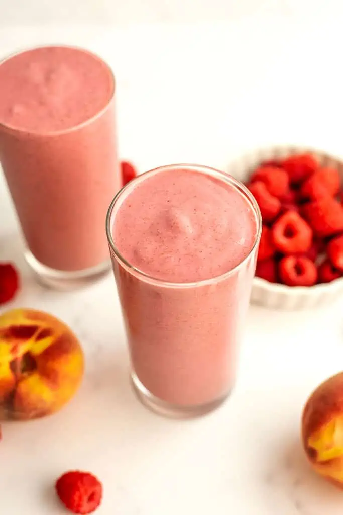 Peach and raspberry smoothie in a tall glass.