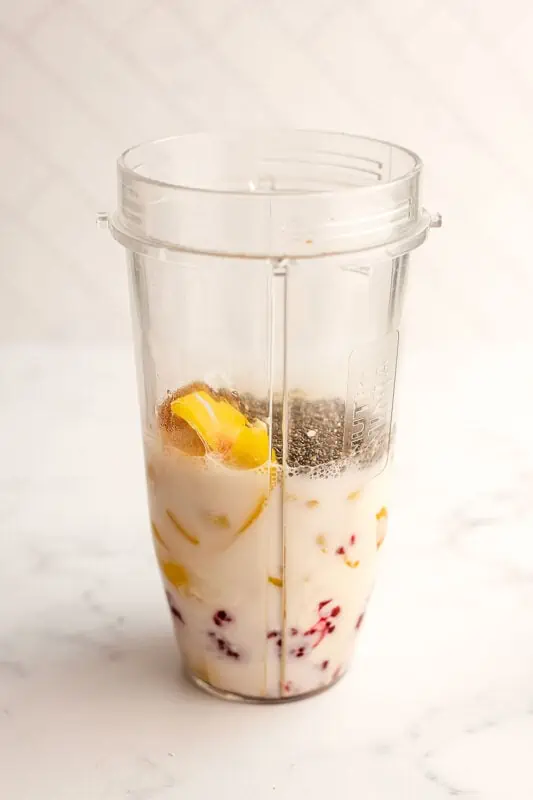 Peach raspberry smoothie ingredients in a blender cup before blending.