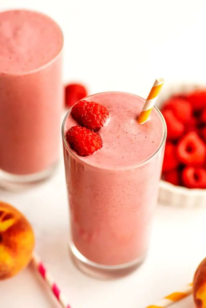 Peach raspberry smoothie with raspberries on top.