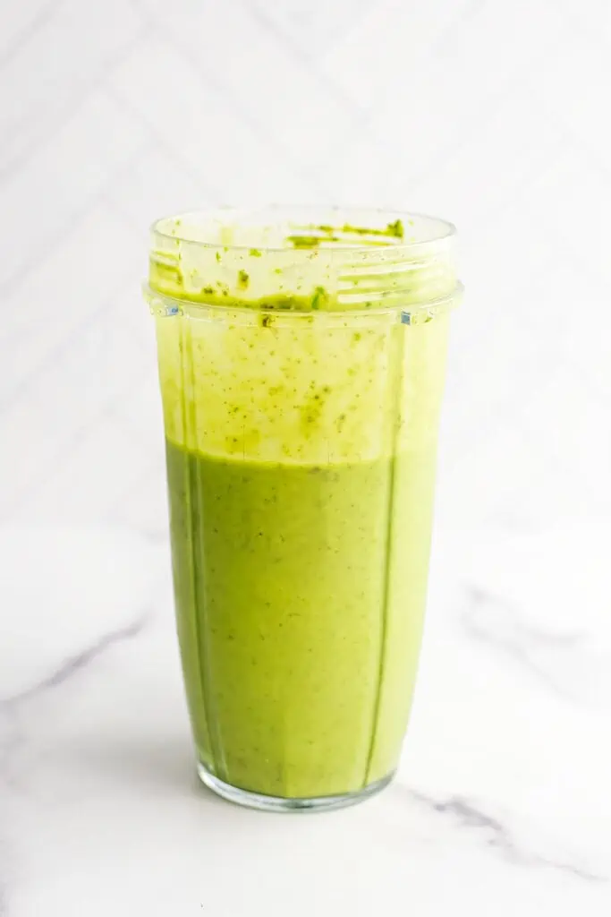 Pineapple banana spinach smoothie ingredients in a blender cup after being blended.