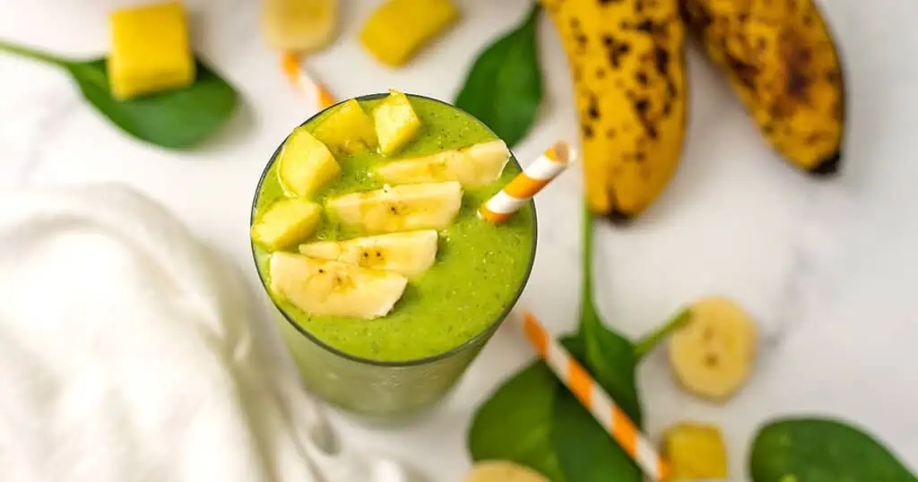 Pineapple banana spinach smoothie with bananas in the background.