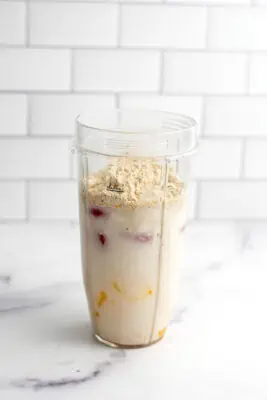 Strawberry mango peach smoothie in a blender cup before being blended.