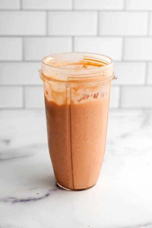 Strawberry mango peach smoothie in a blender cup after being blended.