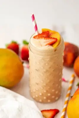 Strawberry mango peach smoothie topped with sliced strawberries and peaches.